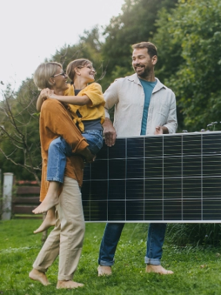 Familie vor Ihrem Eigenheim mit einem Solarpanel.